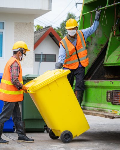 Rubbish cleaner man working with truck loading waste and trash bin.